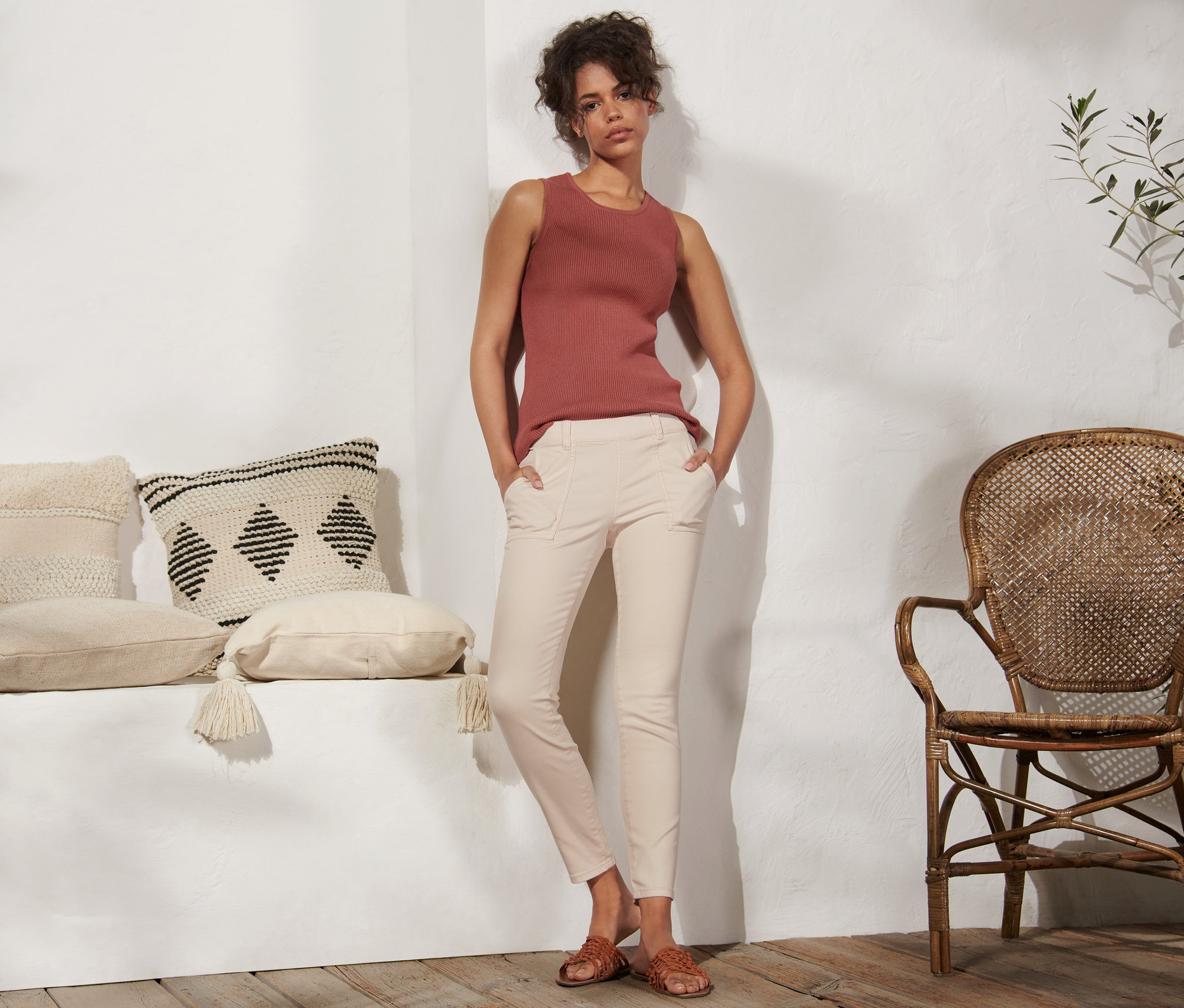 Egy nő áll, kezét a krémszínű női treggings zsebébe dugva.