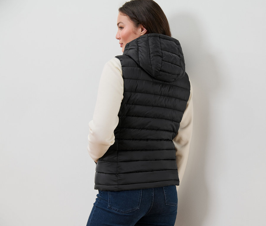 Nő visel kapucnis steppelt mellényt.