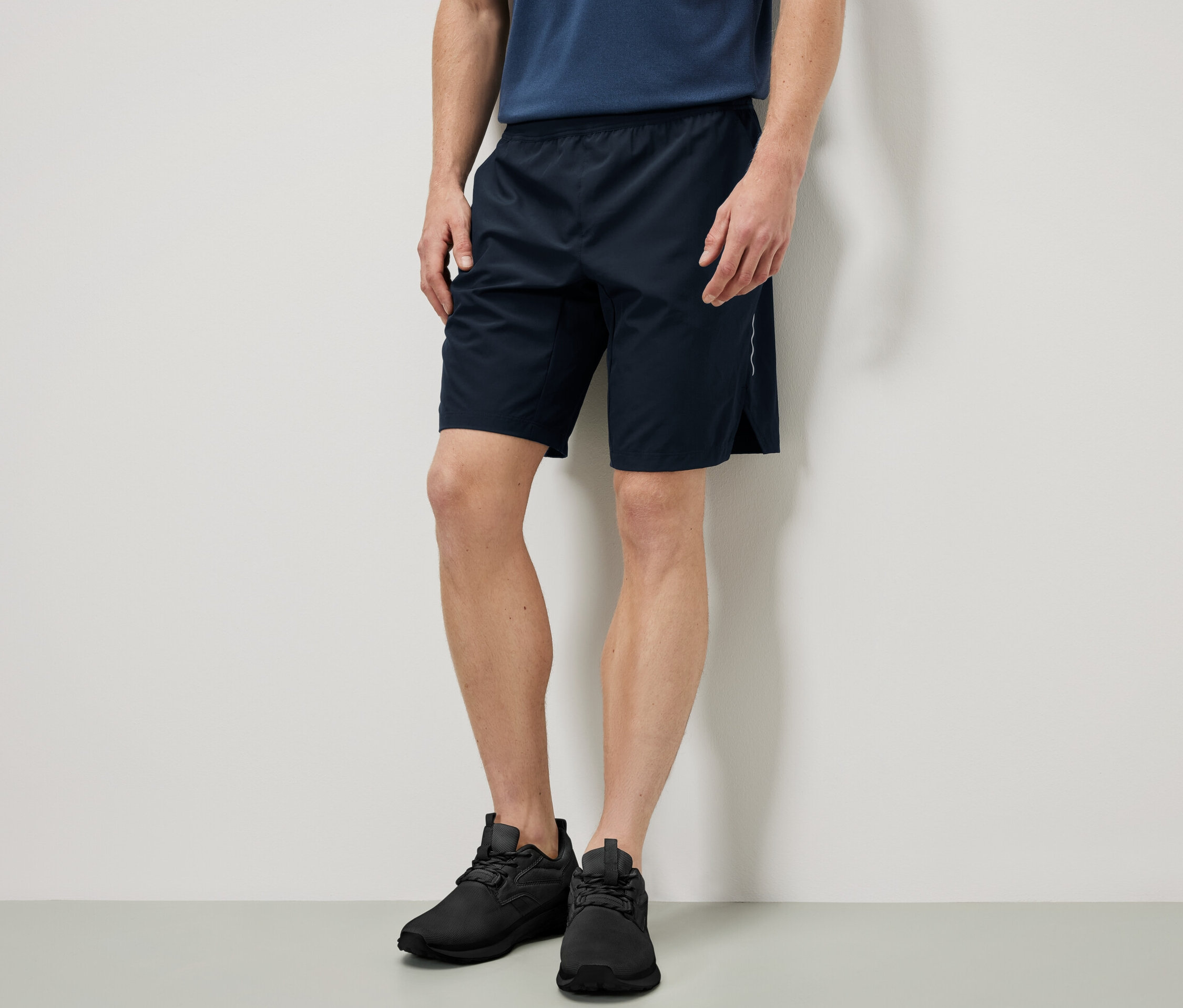 Férfi áll és sport rövidnadrágot visel.