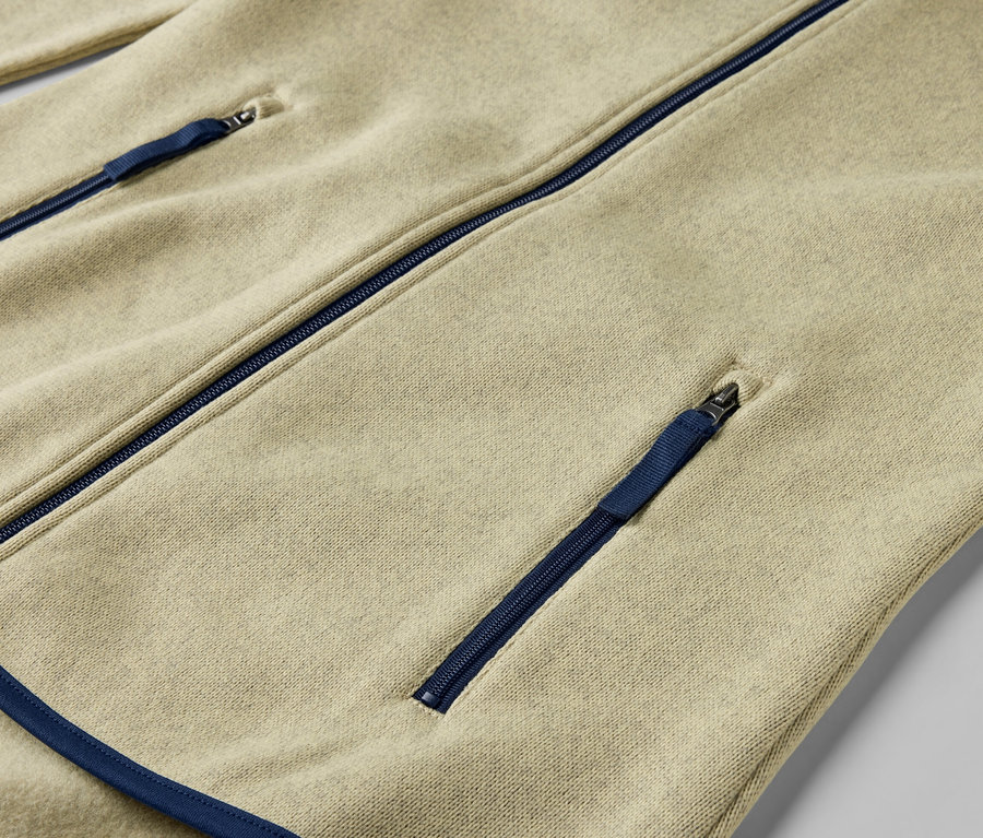 Egy sárga kötött polárfelső részlete kék cipzárakkal.