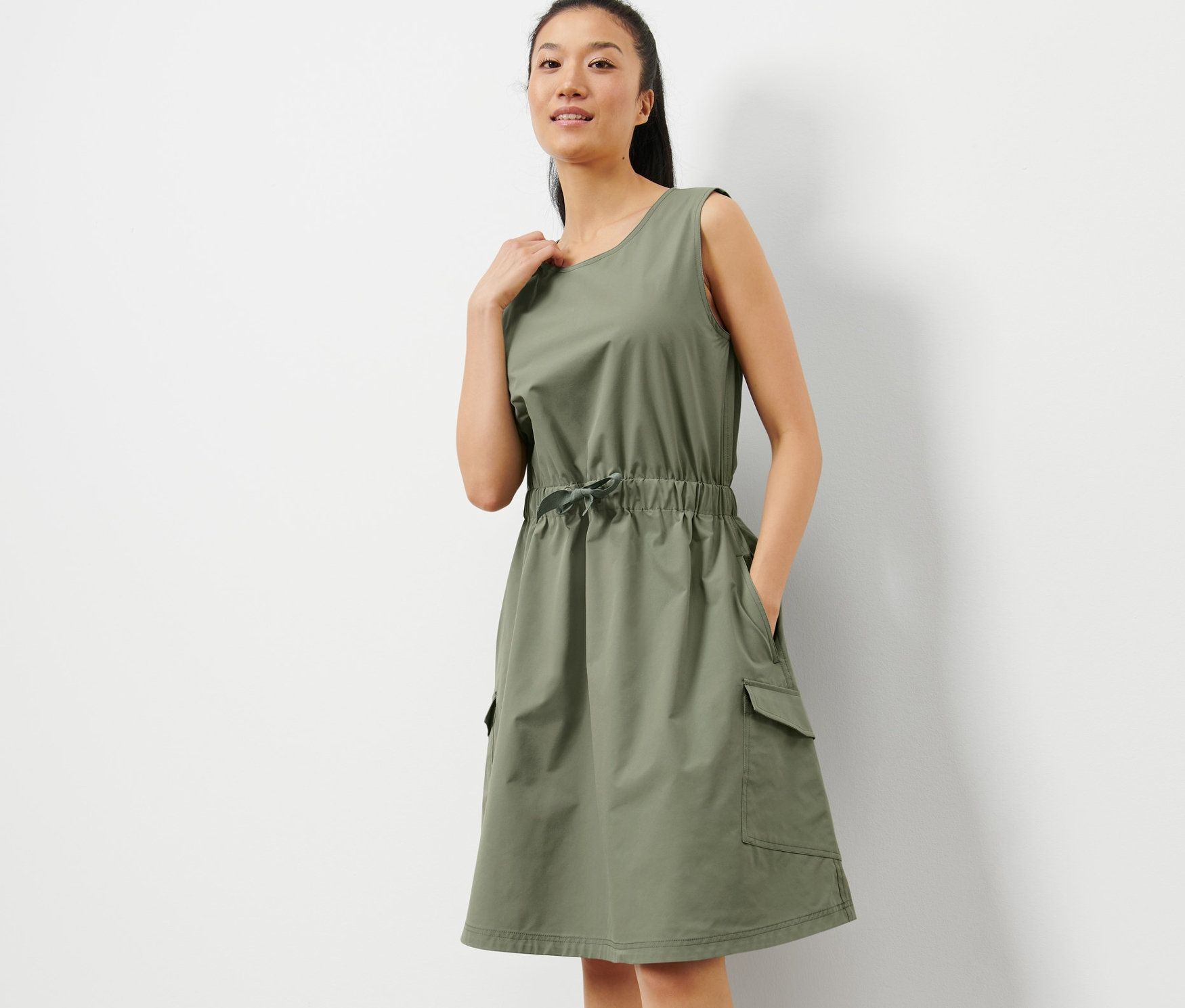 Nő pózol khaki színű funkcionális ruhában.