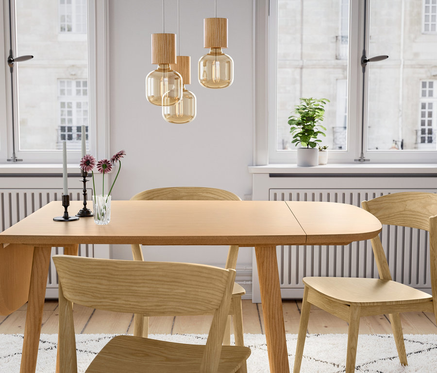 Egy fa étkezőasztal három fa székkel és egy fa függőlámpával.