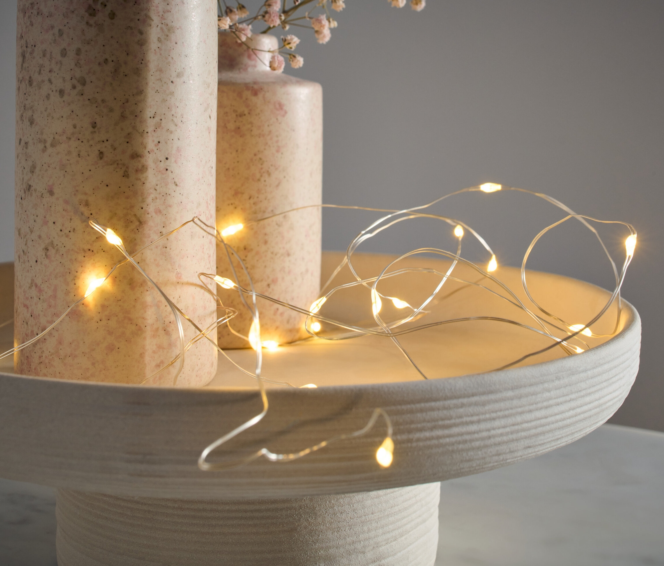 Mikroledes fényfüzér, cseppek, egy dekoratív tálcán fekszik két váza mellett.