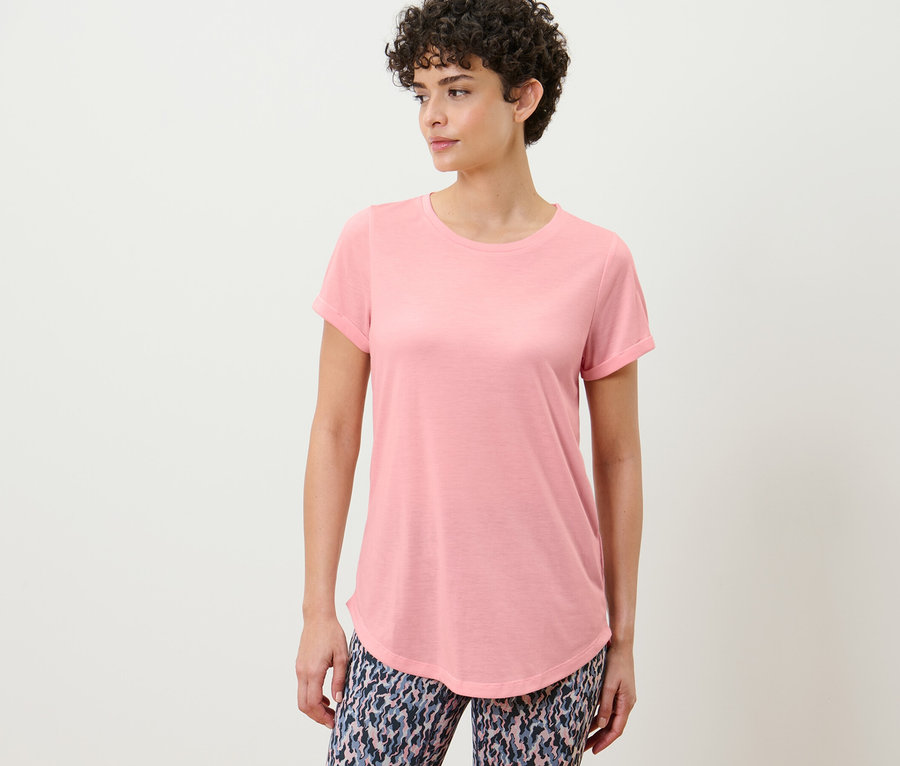 Nő pózol rózsaszín hosszú felsőben.