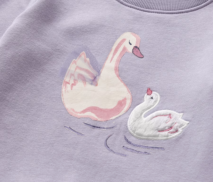 Lila színű, bolyhos belsejű szabadidőfelső gyermekeknek, hattyú mintával.