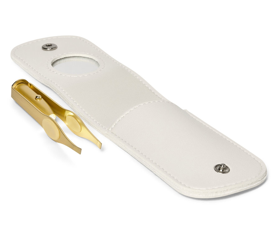 Egy arany színű csipesz egy nyitott fehér tok mellett fekszik.