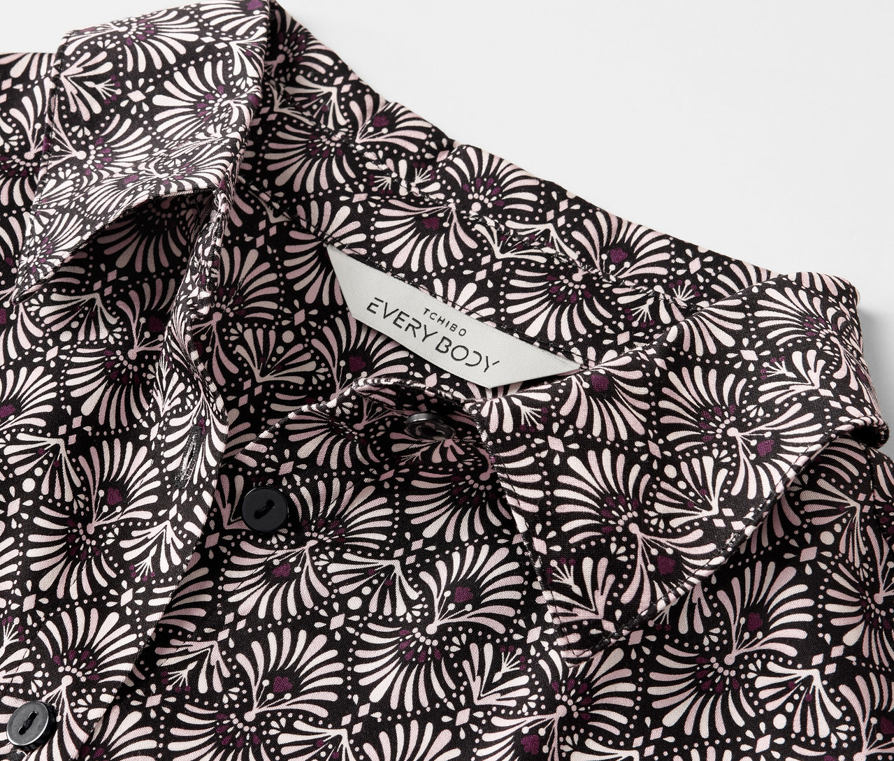 Egy szőtt pizsama részlete fekete-fehér virágmintával és gombokkal.