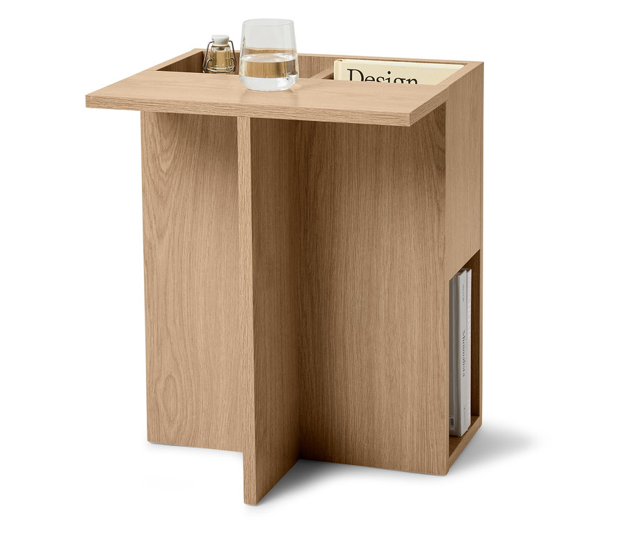 Világos fából készült asztal vízospohárral, lámpával és folyóirattal.