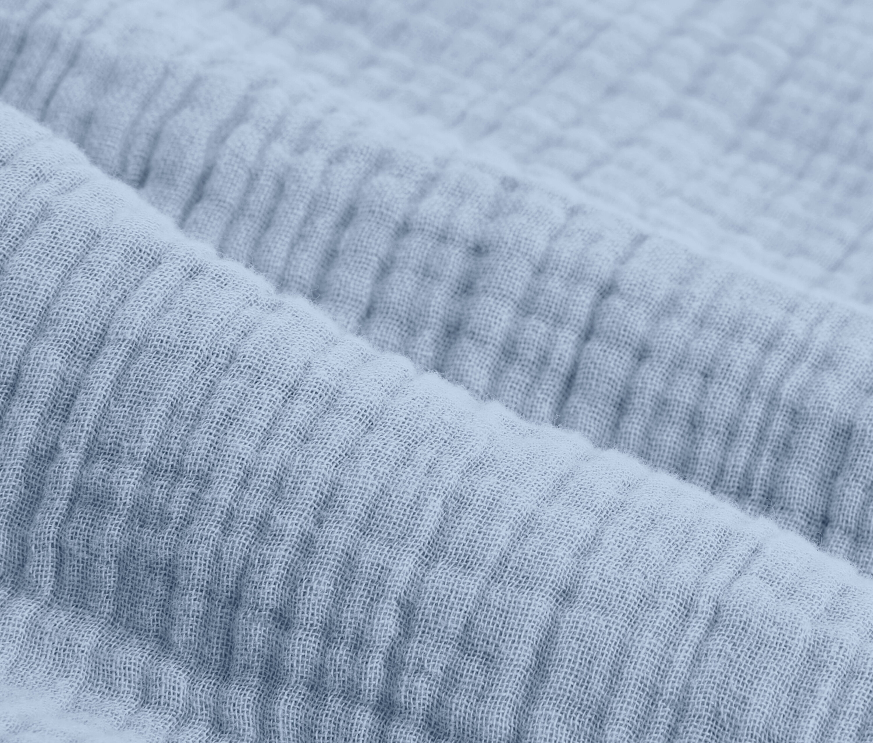 Közeli kép egy világoskék, normál méretű muszlin ágyneműről.