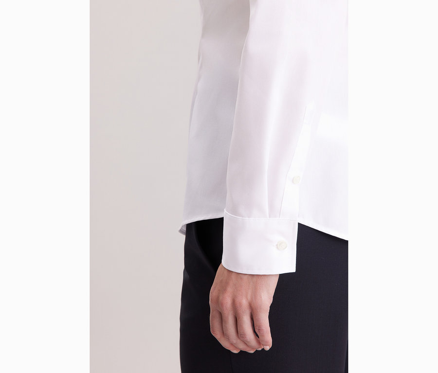 Közelkép egy fehér Seidensticker slim fit szabású, vasalást nem igénylő ingblúzt viselő nőről.