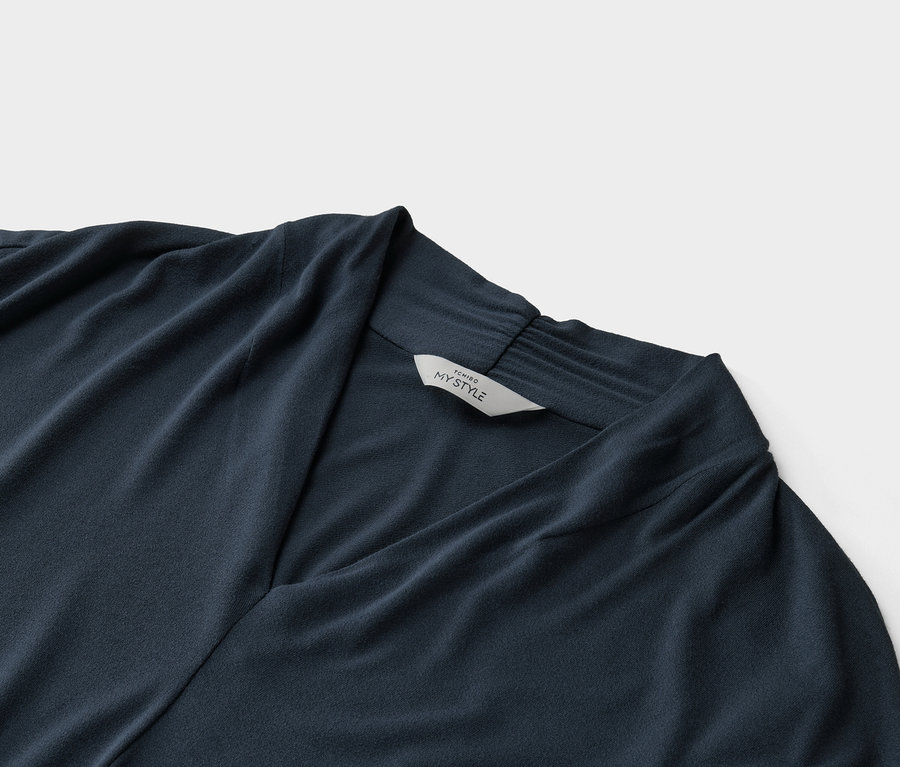 Egy sötétkék, V-nyakú felső közeli képe, rajta egy „Tchibo My Style” feliratú címke.