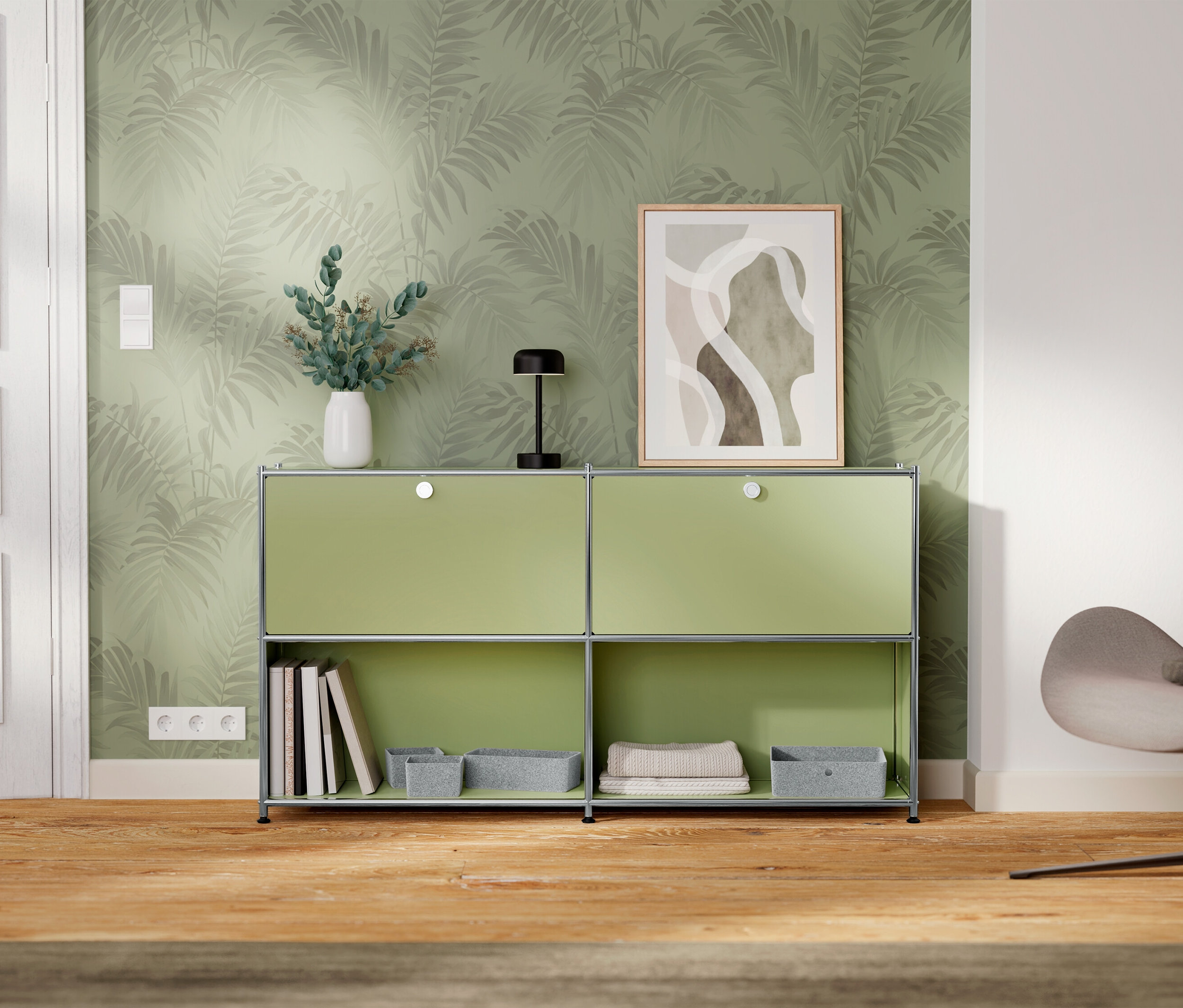 Egy zöld szekrény két rekesszel áll a falnál, melyet levélmintás tapéta díszít.