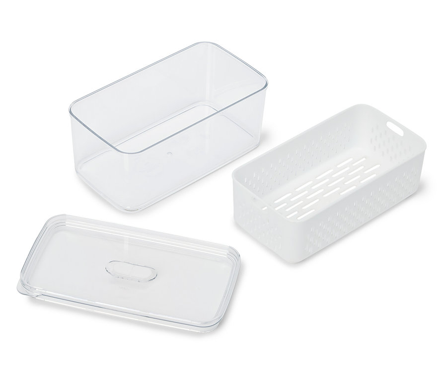 Egy átlátszó tartály, egy fehér, perforált tartály és egy átlátszó fedél fekszik egy fehér felületen.