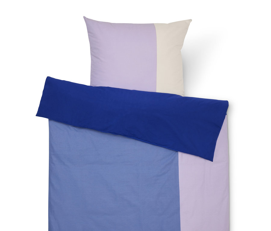 Ágyneműgarnitúra kék huzattal, lila és krémszínű párnahuzattal.