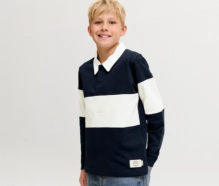 Mosolygó szőke fiú visel egy sötétkék-fehér csíkos Jack&Jones Polo Pulóvert fehér gallérral.