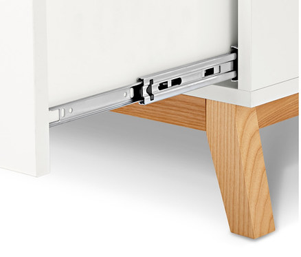 Egy fehér komód részlete nyitott fiókkal és fa lábakkal.