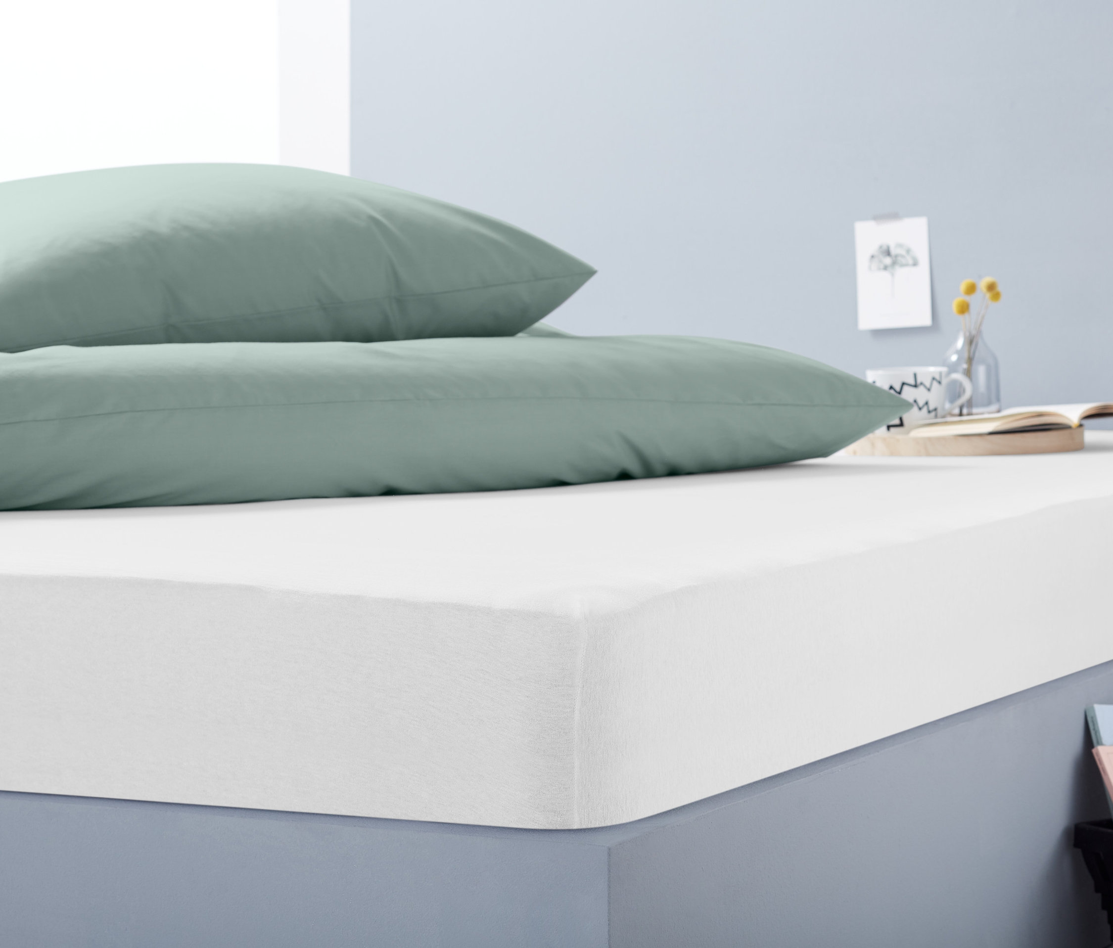 Két zöld párna egy fehér Jersey gumis lepedőn, zöld extra.