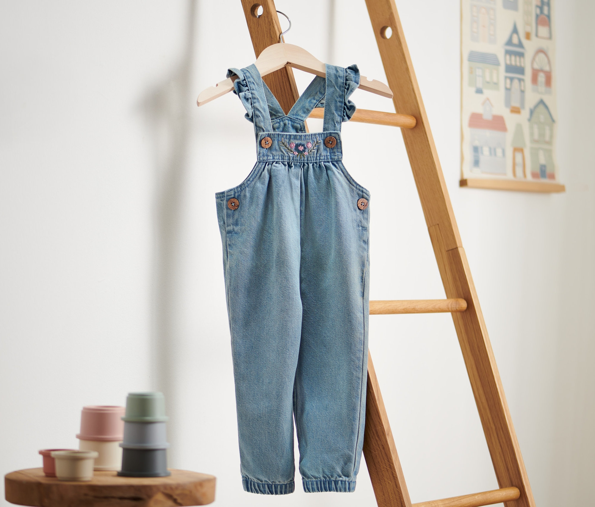 Egy kislány kantáros farmernadrág lóg egy falétrán.