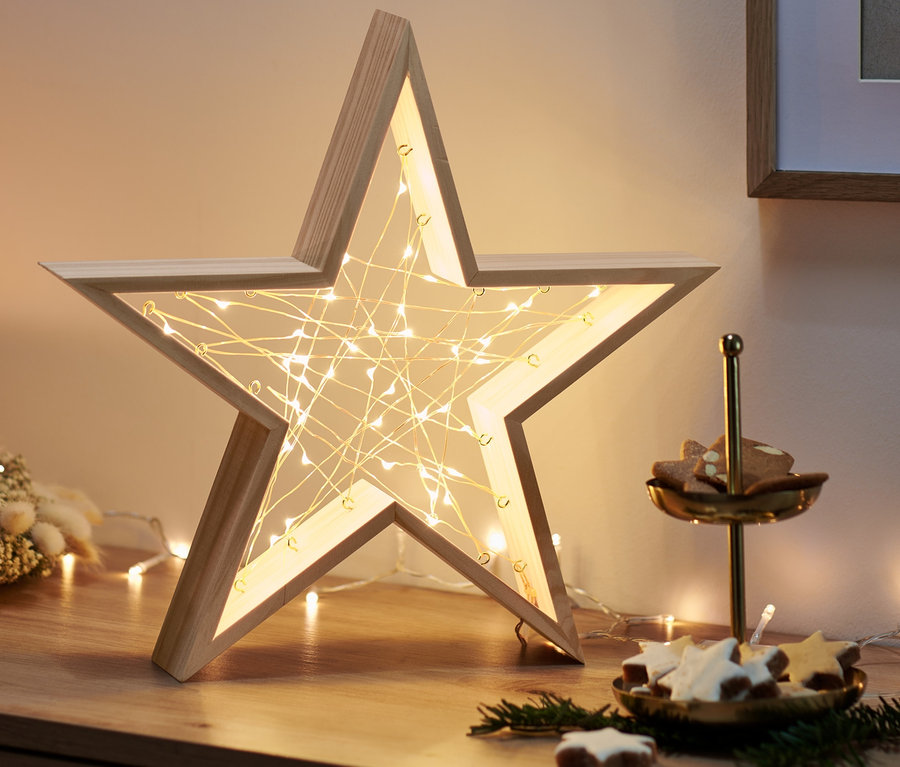 Egy fa komódon egy LED-es facsillag, egy adventi koszorú gyertyával és egy süteményes tálca található.