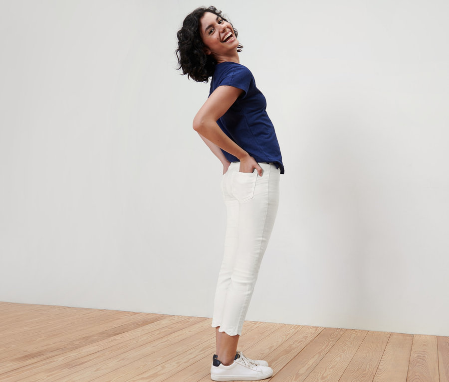 Nő pózol 7/8-os, lyukhímzéses treggingsben és kék pólóban.