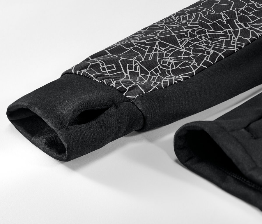 A fényvisszaverő fekete női termodzseki részlete, fekete szegéllyel és geometriai mintával az ujján.