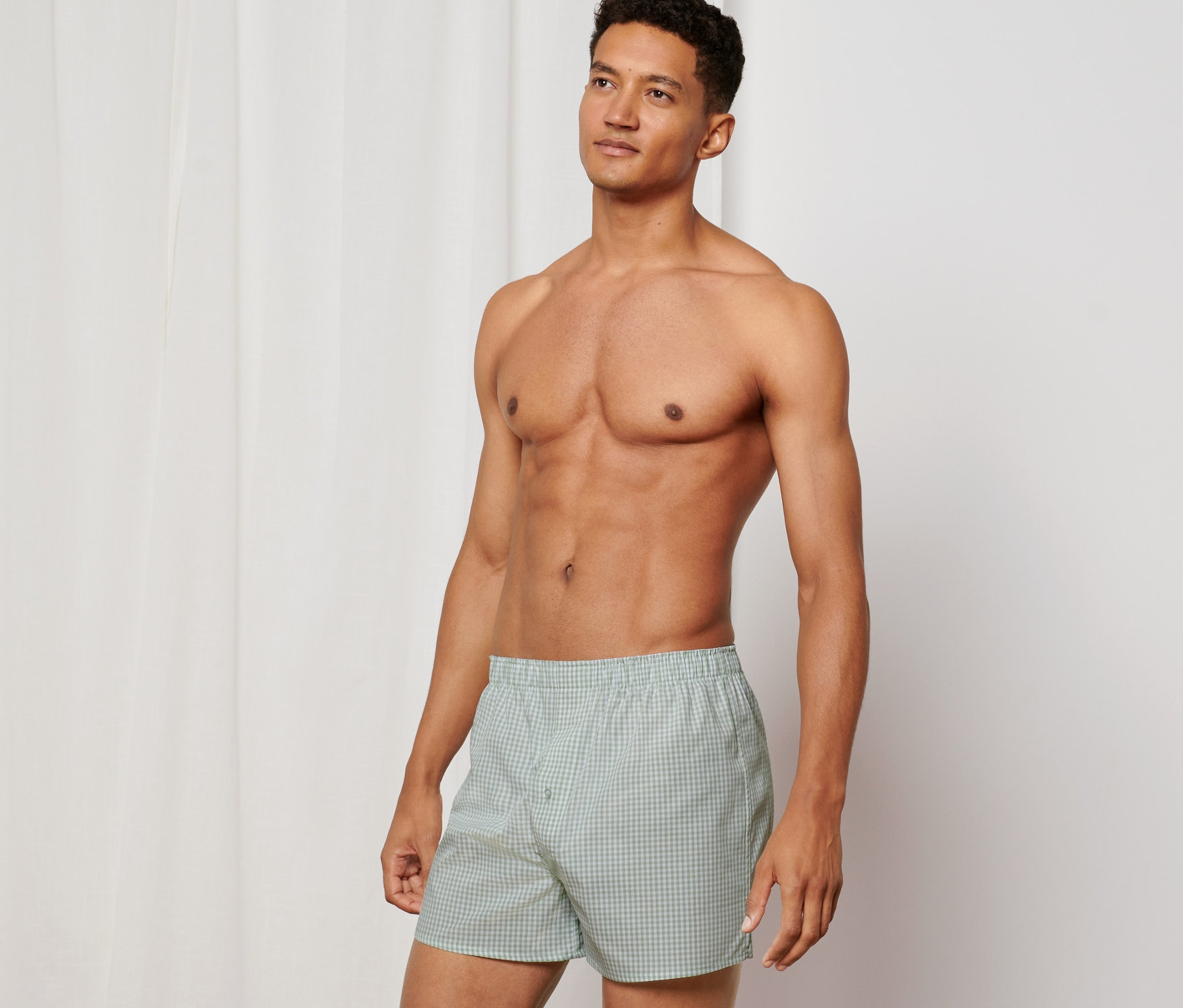 Férfi pózol meztelen felsőtesttel és 2 férfi szövött boxeralsó szettben, kockás, zöld.