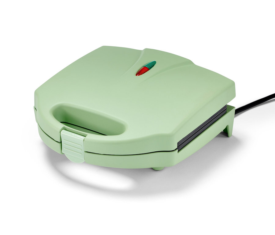 Egy zárt, világoszöld gofrisütő fekete kábellel.