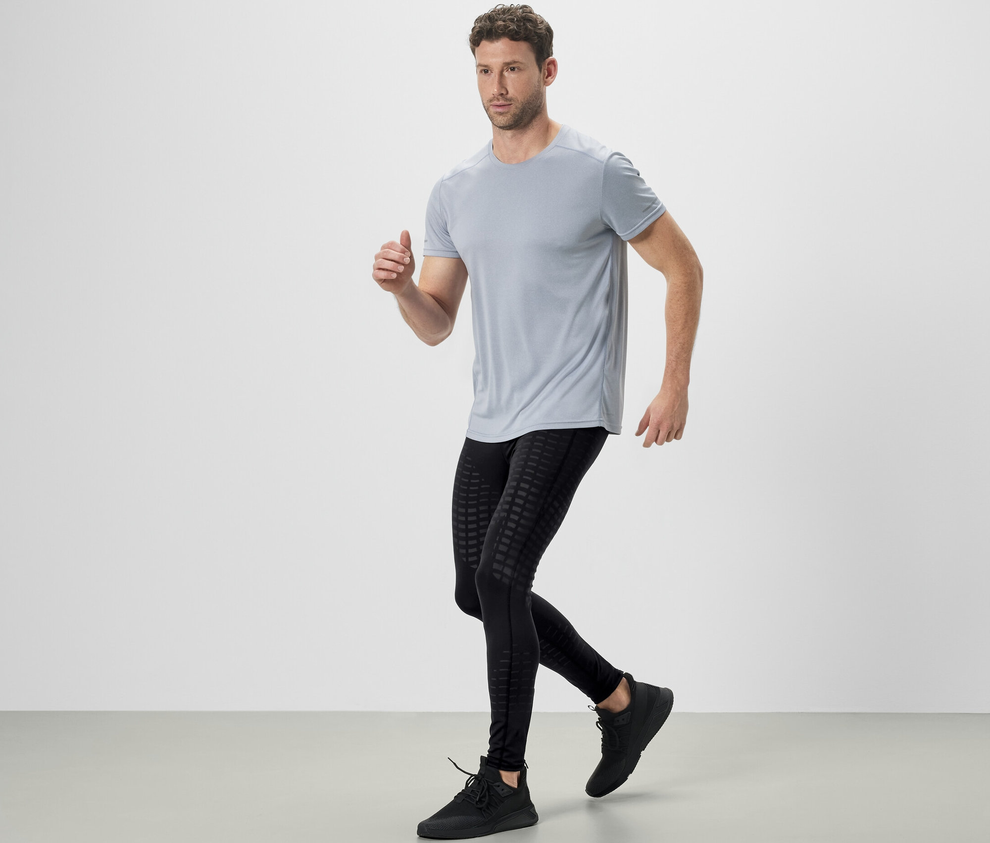 Férfi szürke pólóban és fekete futónadrágban fut.