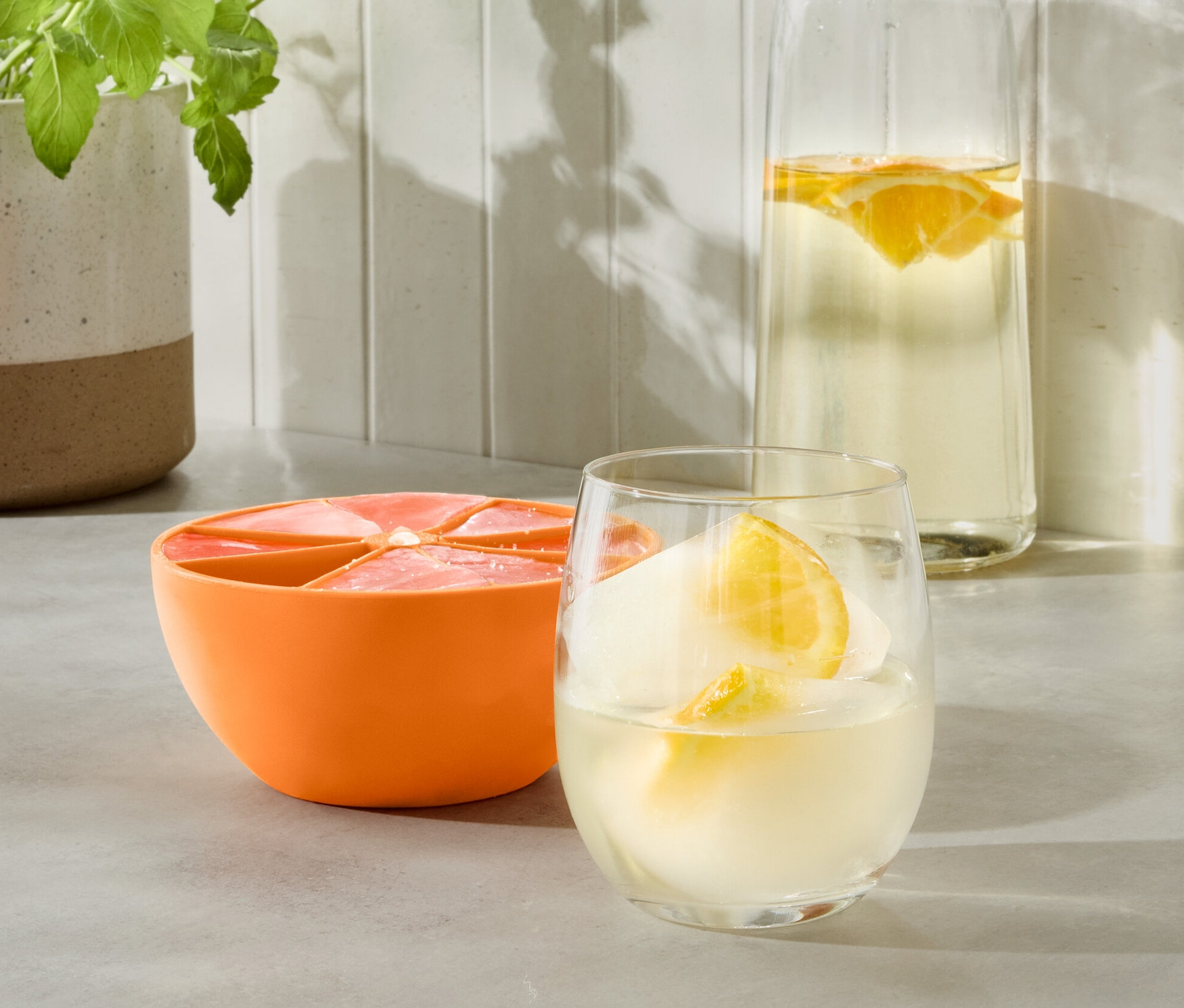 Narancssárga XL jégkockakészítő egy pohár itallal és egy vizes palackkal.