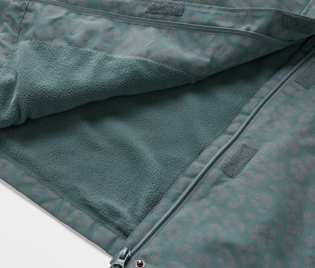 Egy nyitott, fényvisszaverő elemekkel ellátott gyerek termo esőkabát részlete, amely a belső polár anyagot mutatja.