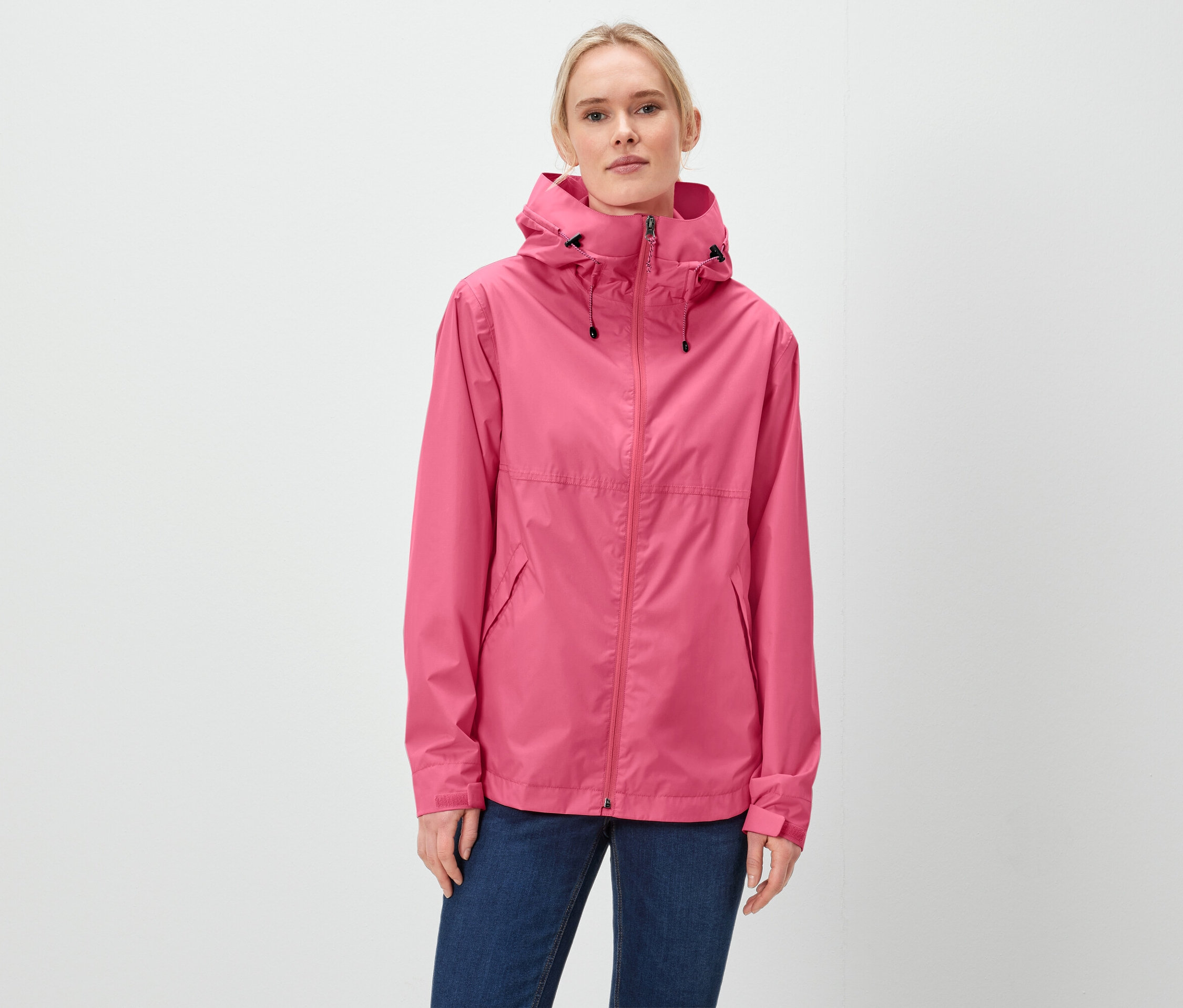 Egy nő rózsaszín kapucnis kabátot és kék farmert visel.