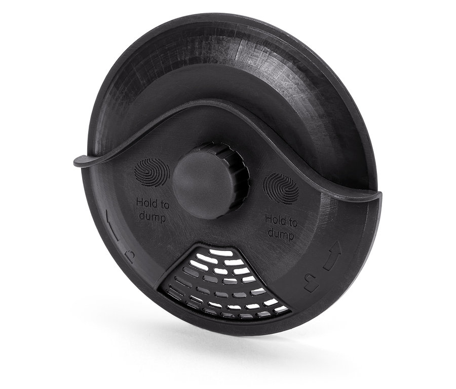 Közeli kép egy fekete műanyag fedélről "Hold to dump" felirattal és ráccsal.