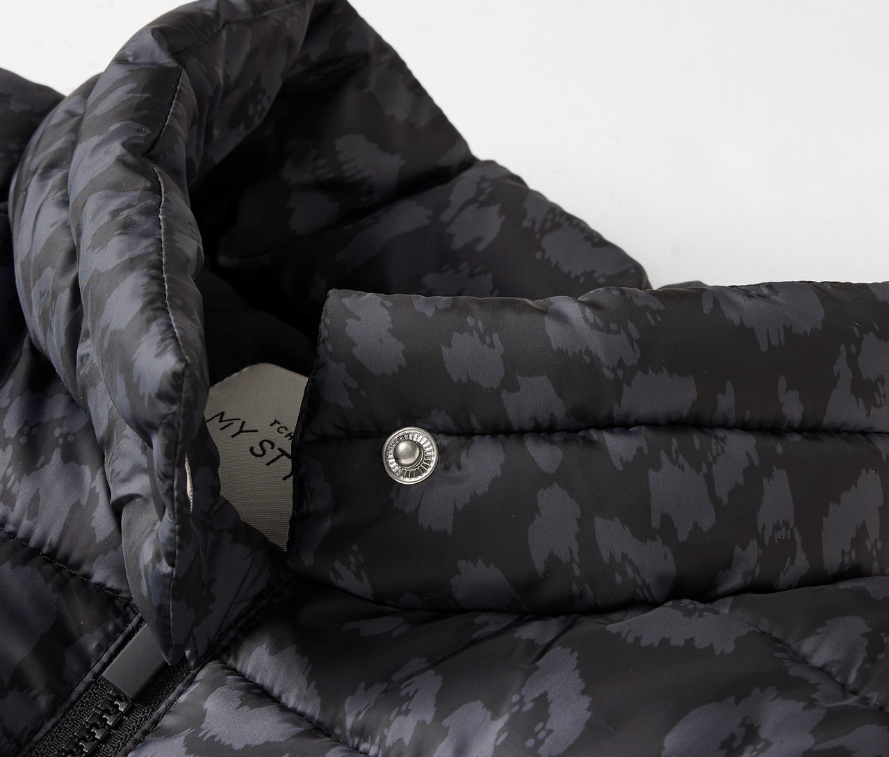 Egy fekete, mintás steppelt kabát részlete.