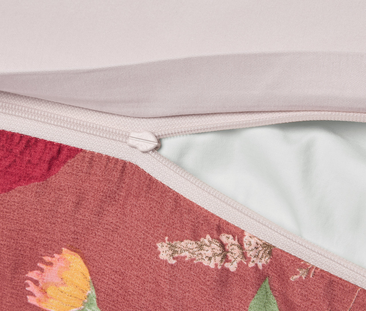 Közelkép egy virágmintás párnahuzatról cipzárral.