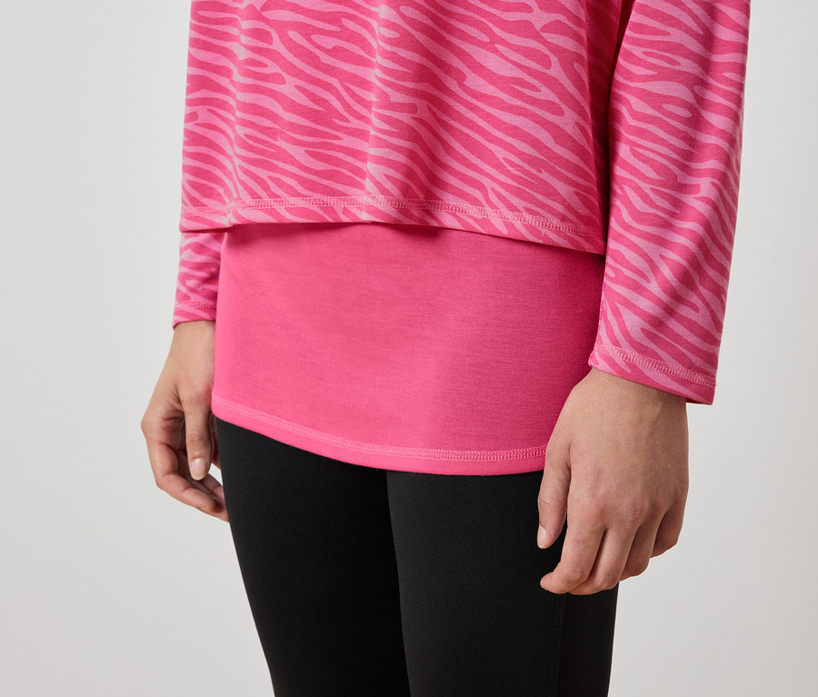 Egy nő részlete rózsaszín, állatmintás felsőben és fekete leggingsben.