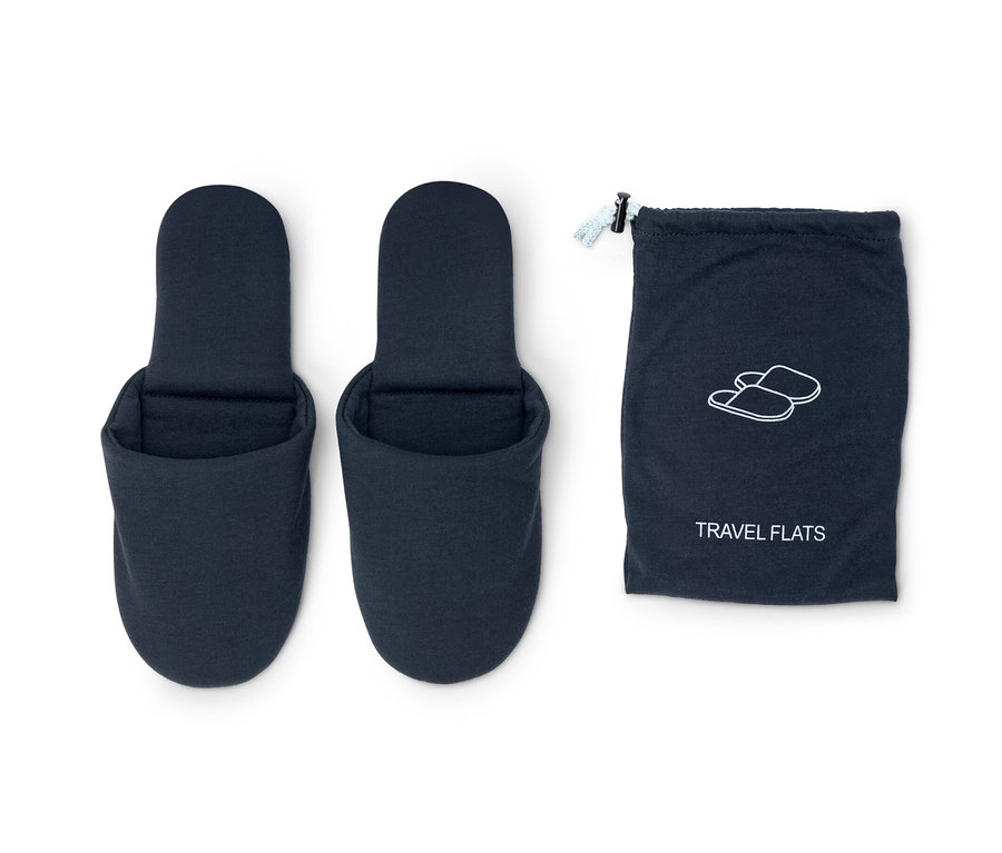 Két kék utazópapucs egy kék tasak mellett.