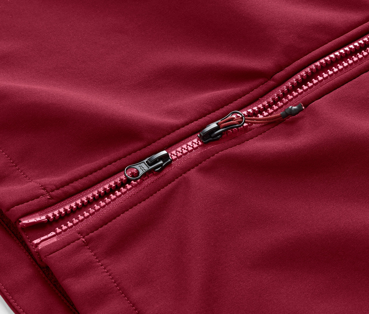 Egy sötétpiros softshell kabát cipzárjának részlete.