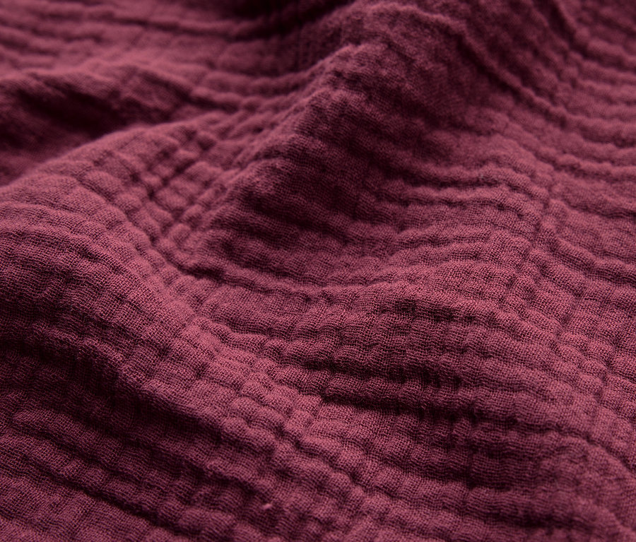 Közelkép egy bordó színű anyag textúrájáról.