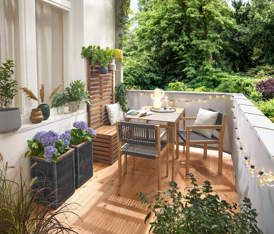 Erkély berendezése textilfonatos erkélygarnitúrával, szürke erkély belátásgátlóval és szélvédővel, LED-es kültéri fényfüzérrel hálózati adapterrel, textilfonatos virágcseréppel, LED-es kültéri akkumulátoros asztali lámpával, kaktusszal és 2 vászonhatású kültéri párnával.