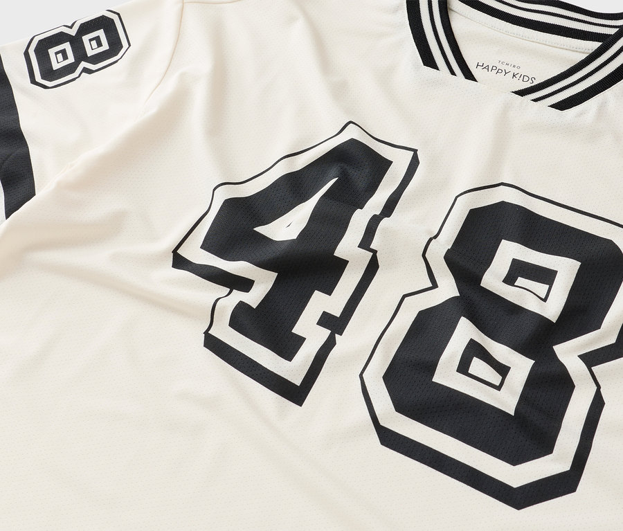 Egy krémszínű póló közeli képe, fekete 48-as számmal.