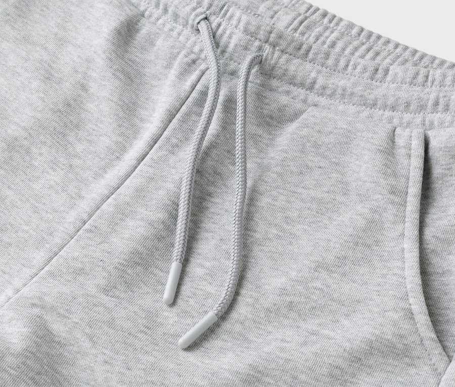 Egy szürke színű, húzózsinórral és zsebbel ellátott jogging nadrág részletfotója.