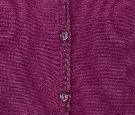 Egy fukszia színű, finomkötésű női kardigán részlete két gombbal.