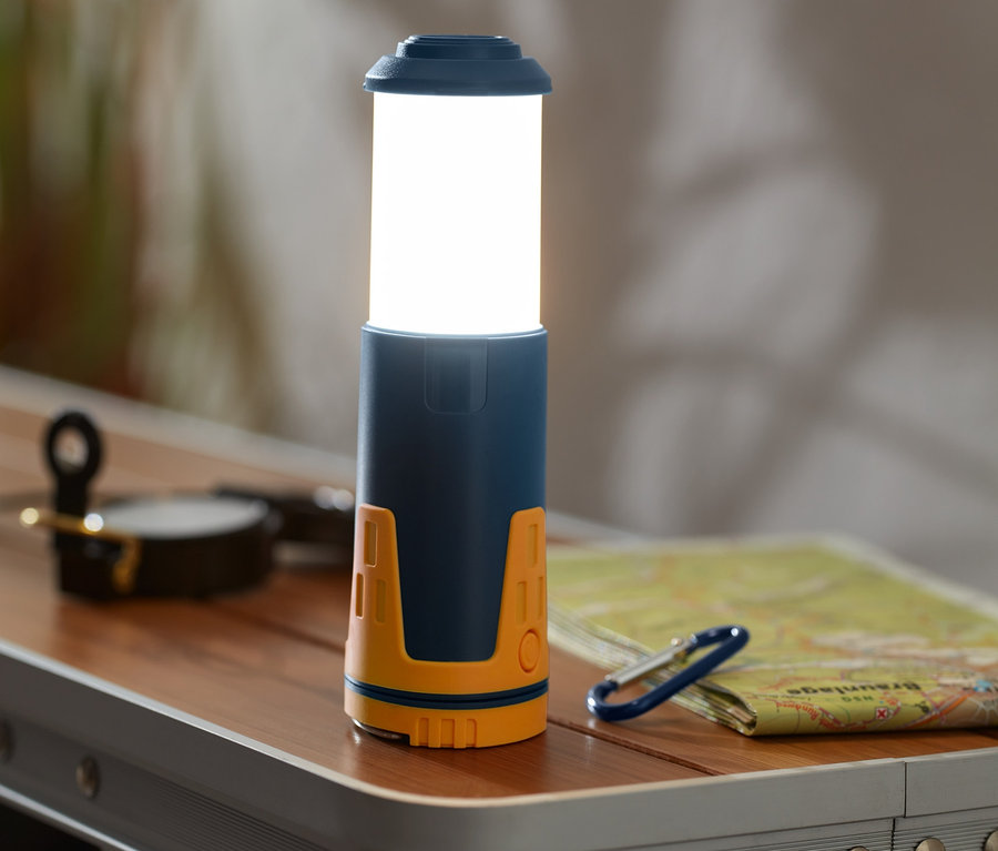 Egy teleszkópos kempinglámpa áll az asztalon.