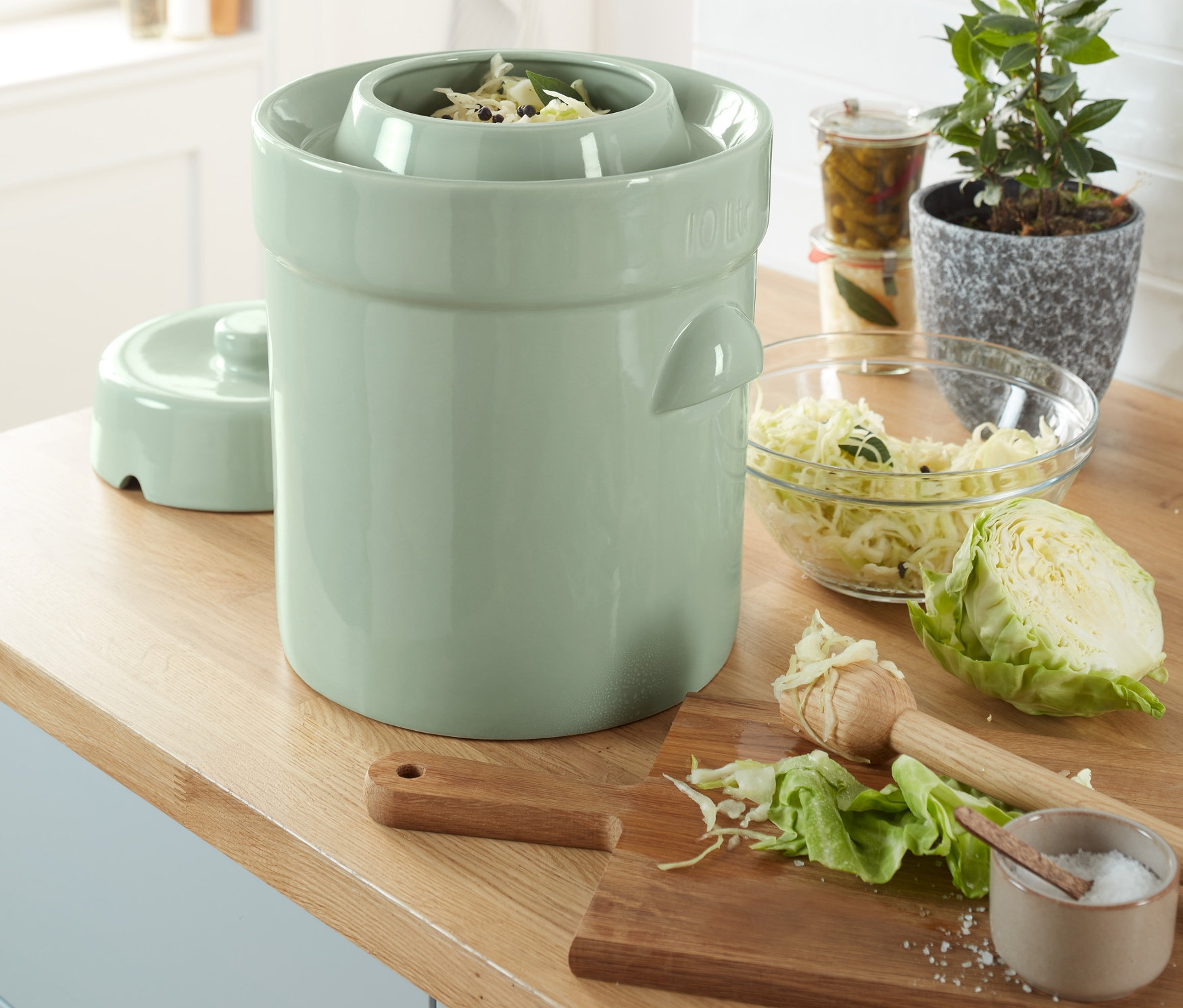 Savanyú káposzta készül egy kerámia fermentáló edényben.