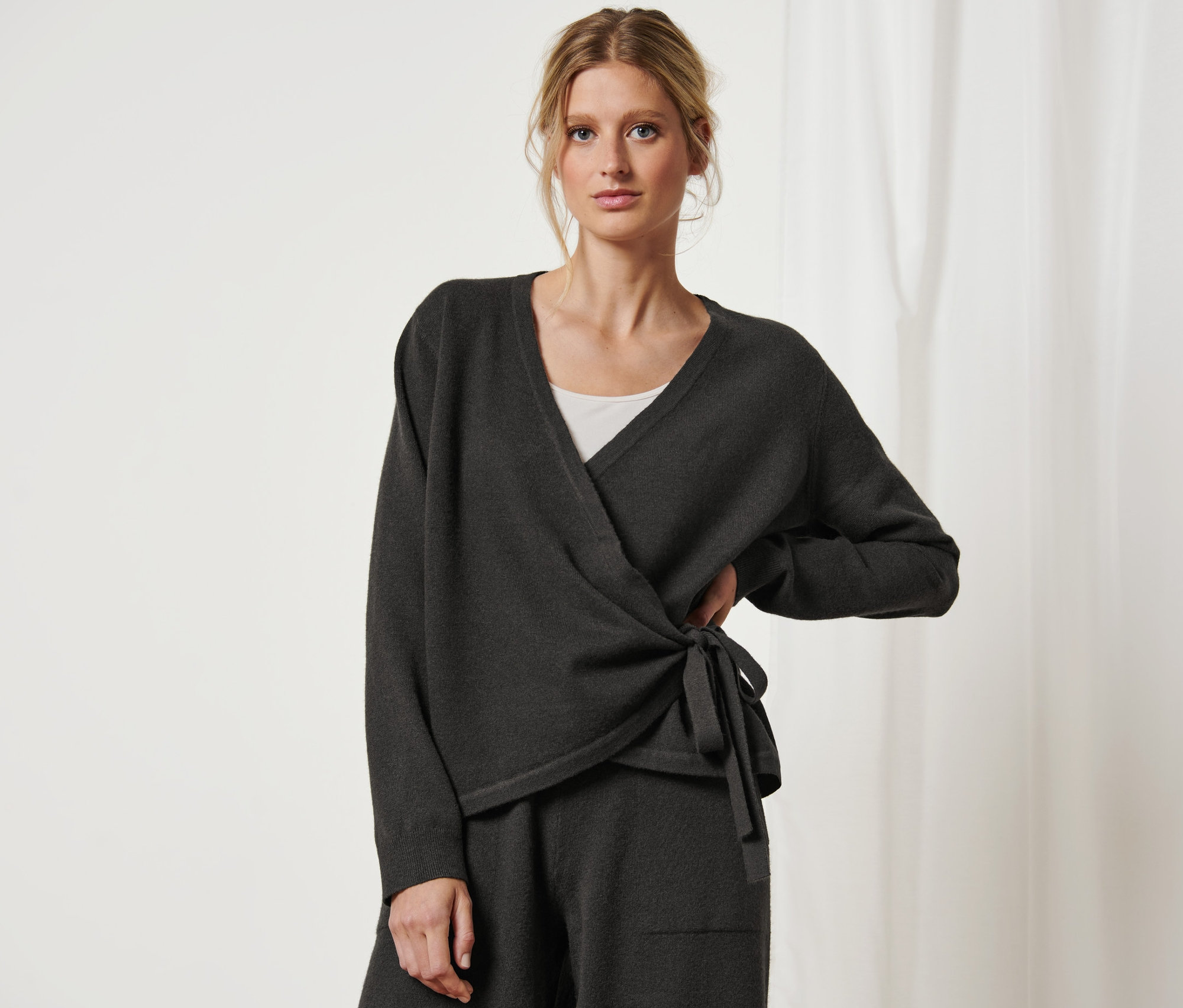 Nő pózol átlapolós kardigánban.