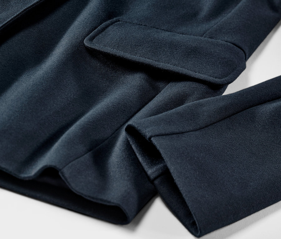 Egy sötétkék női jersey blézer részletének közeli képe.