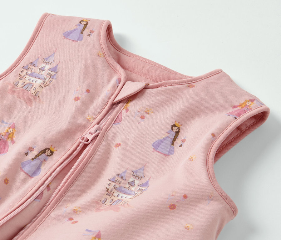 Egy rózsaszín, lábakkal ellátott hálózsák részlete, hercegnőkkel és kastélyokkal nyomtatva.