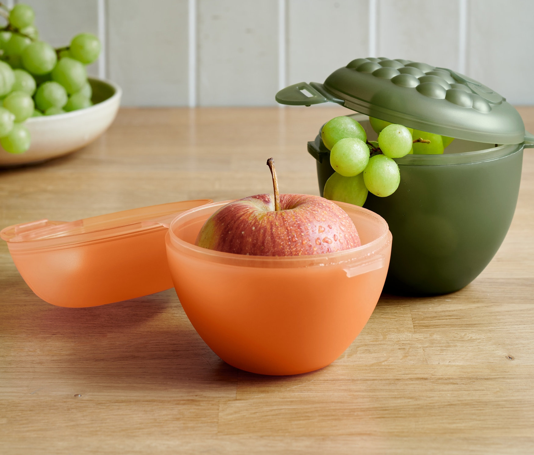 Alma egy narancssárga, szőlő egy olívazöld 2 gyümölcstartó dobozban.