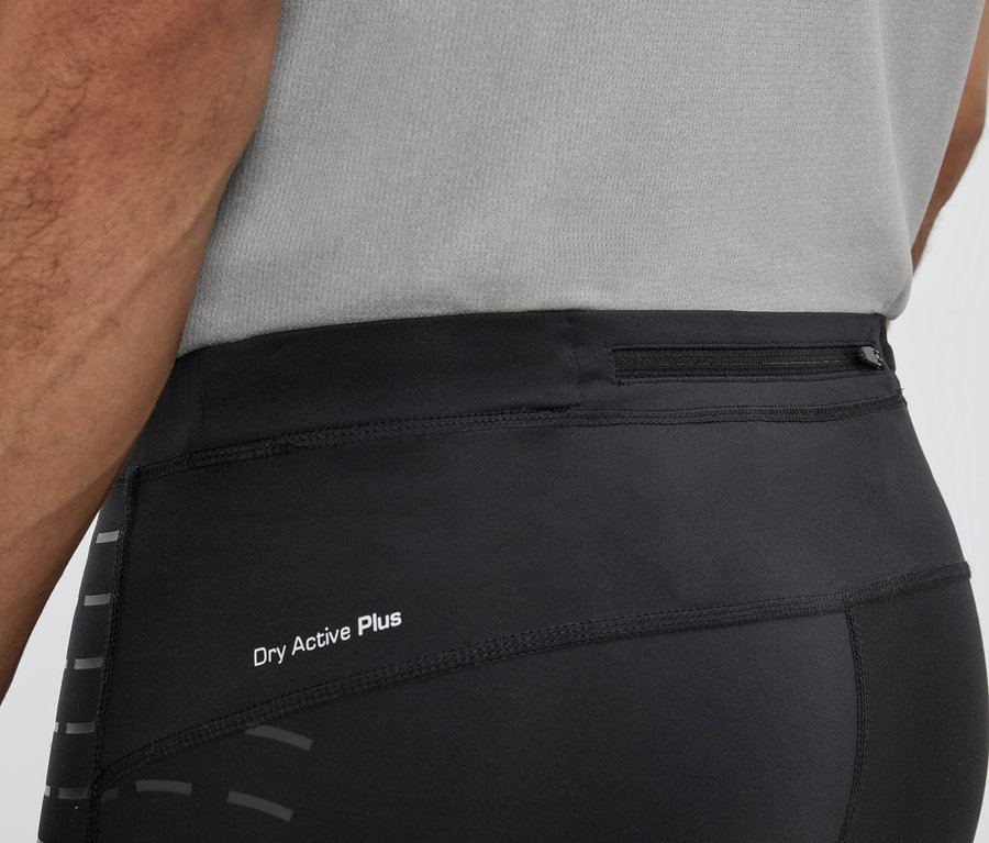 Férfi visel fekete leggingset Dry Active Plus felirattal és cipzáras zsebbel a derékrészen.