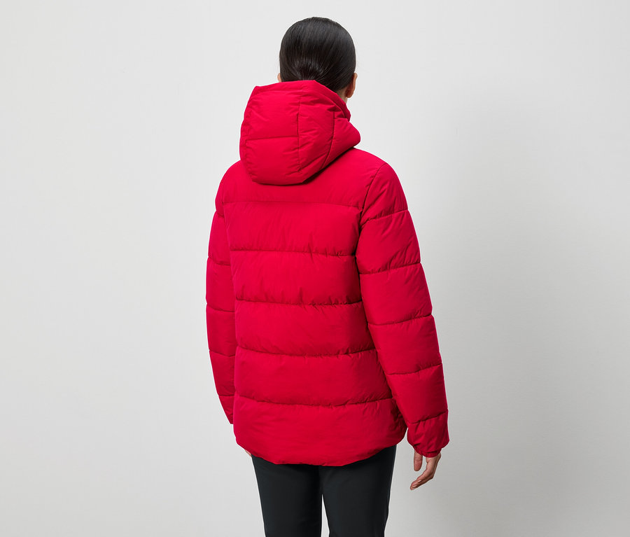 Egy személy, háttal a kamerának, piros, kapucnis, pehelykabátot és fekete nadrágot visel.